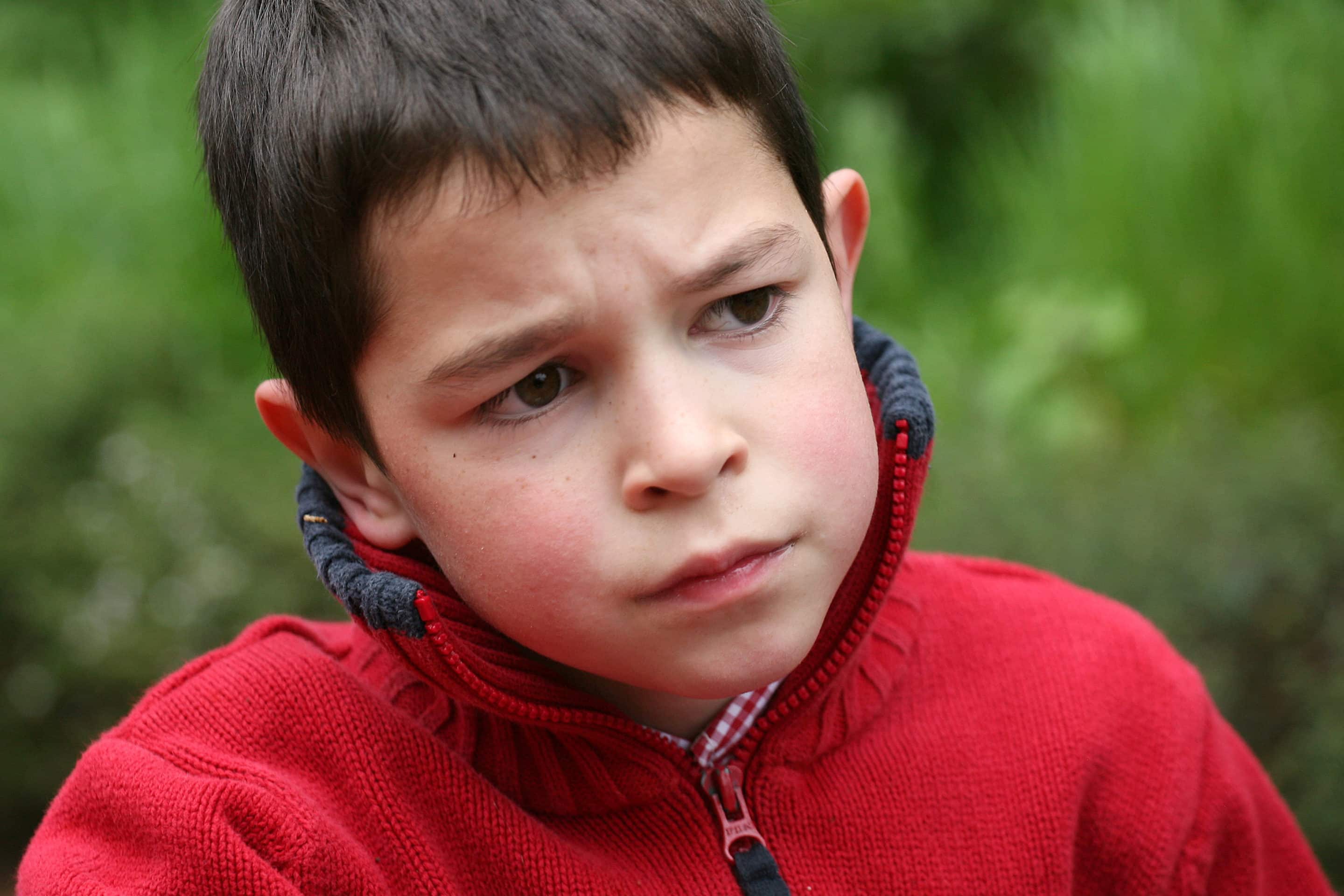 Expression triste d'un garçon, illustrant l'impact du comportement toxique d'un pervers narcissique sur les enfants.