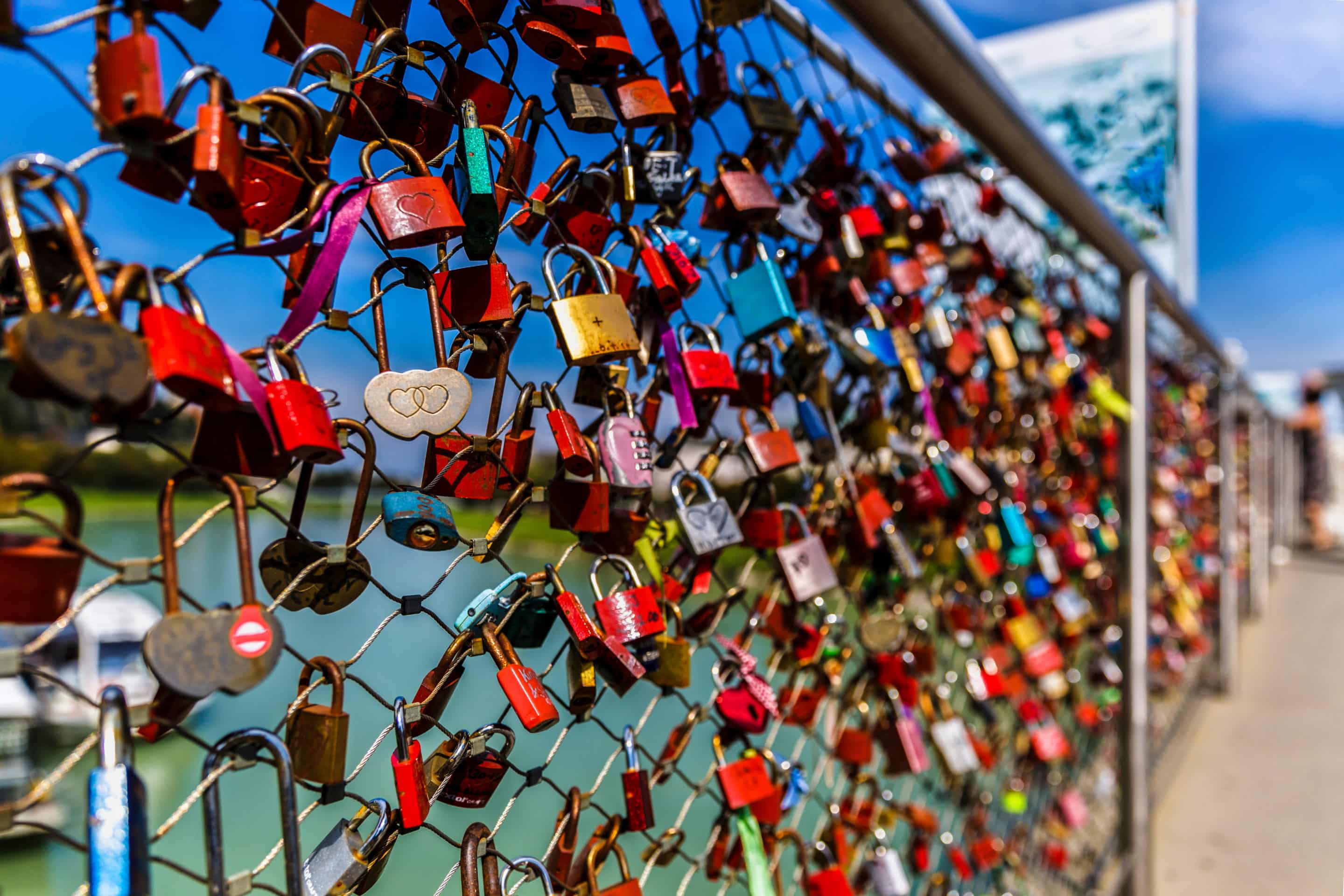 Grillage couvert de cadenas d’amour colorés, symbolisant l’emprise émotionnelle et le love bombing.