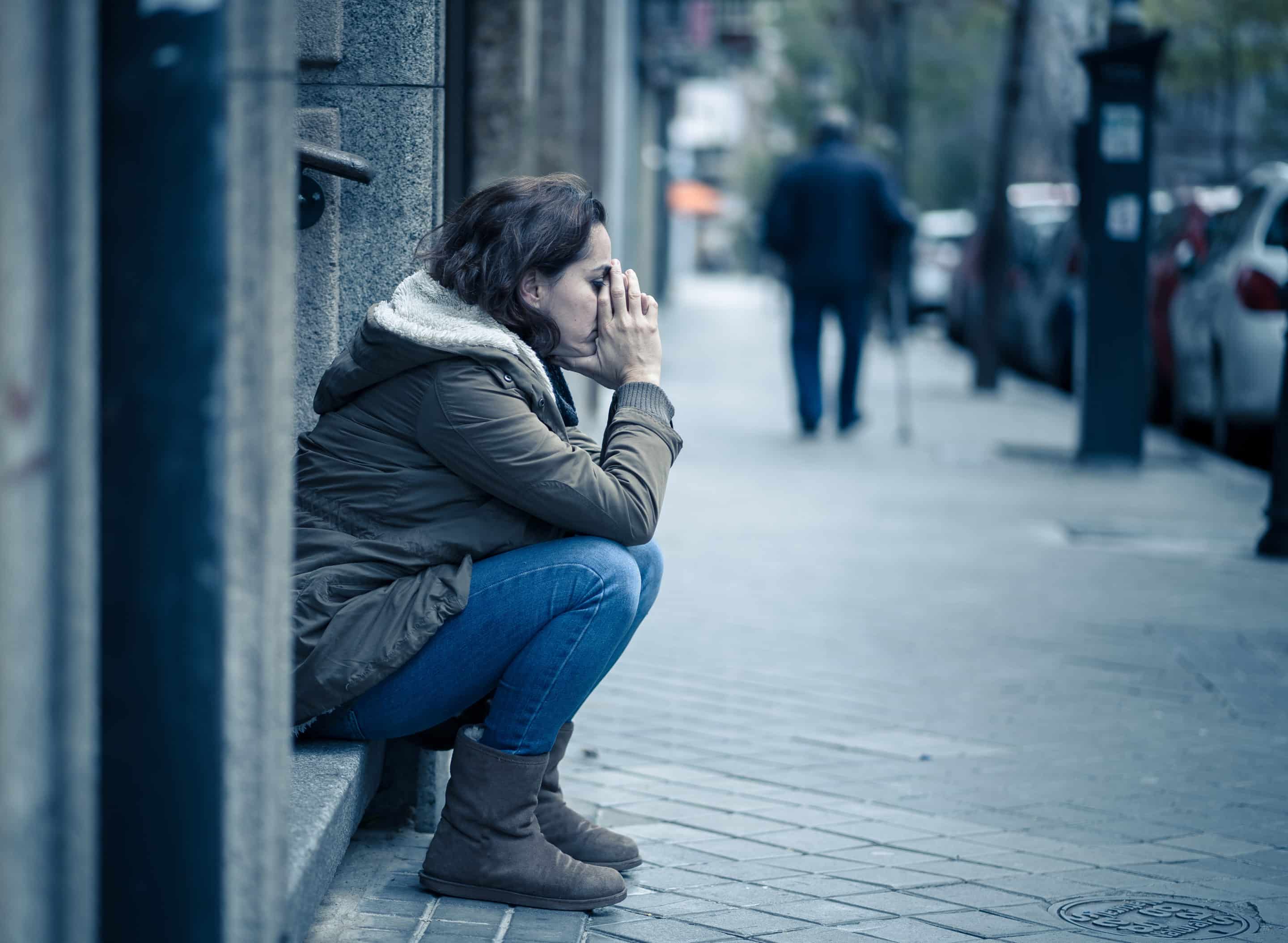 Photo d’une femme assise dans la rue, exprimant la détresse et le renoncement face à l’impact de la perversion narcissique.